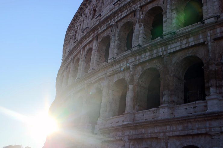 The rising sun behind the Colosseum